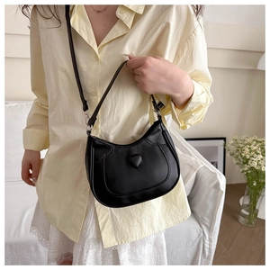 Detail of black PU leather crossbody bag featuring a 3D heart decor and silver hardware