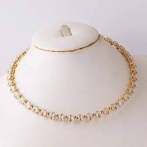 Detail of elegant gold tennis necklace with oval cubic zirconia on a white mannequin