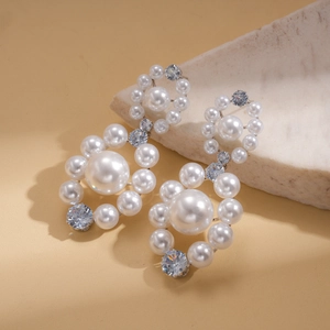 Detail of layered pearl drop earrings with sparkling zircon stones on a stone pedestal