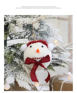 Dettaglio di un pupazzo di neve in peluche con cappello rosso appeso a un albero di Natale