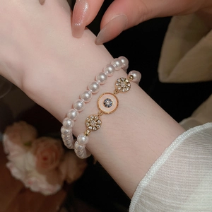 Détail de bracelets en perles plaqués or 18k avec œil en émail et breloques en zircon