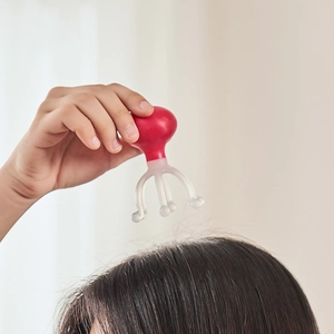 Red octopus-shaped manual head massager with ergonomic handle for scalp relaxation