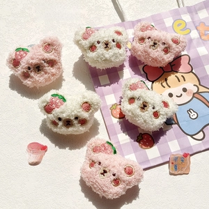 Detail view of plush strawberry bear pins in pink and white with fine embroidery
