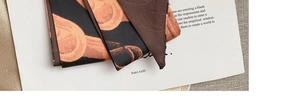 Detail of silk scarf with vintage orange chain print on deep brown and black fabric