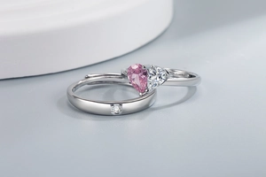 Detailed close-up of pink and white heart-shaped matching rings for couples in silver