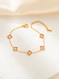 Detail of adjustable gold bracelet with square emerald-cut zircons on textured stone fabric