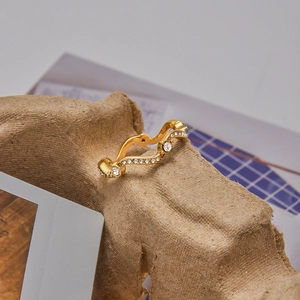 Détail macro d'une bague vague en acier inoxydable doré 18K avec zircons blancs