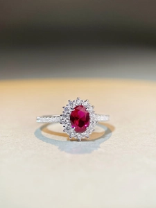 Macro view of oval pigeon blood red stone with halo diamond setting and silver band