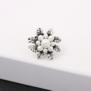 Macro shot of vintage snowflake pearl brooch with intricate silver engraved texture