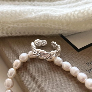 Macro shot of S925 sterling silver twisted braided ring resting on white pearls