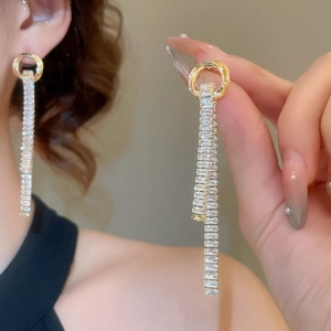Detail of elegant gold tassel earrings with square cubic zirconia and long chain drop