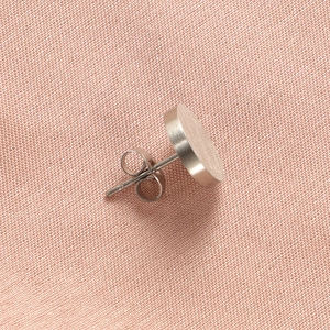 Close-up of silver round brushed stainless steel studs on pink woven fabric