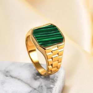 Detail of gold square malachite ring with watch strap band on marble and silk surface