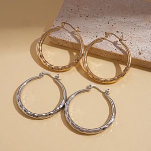 Geometric textured hoop earrings in gold and silver finish on a minimalist stone base