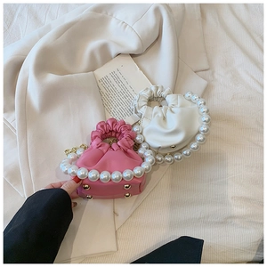 Detail of elegant pleated mini handbags with pearl handles in pink and white colors