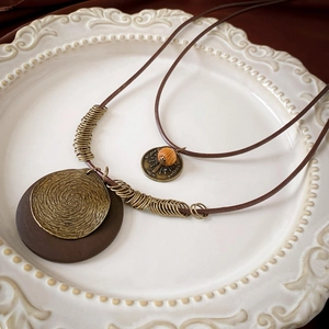 Detail of bohemian double-layer necklace with vintage bronze discs and wooden pendants