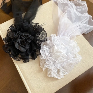 Detailed macro view of black and white lace flower headpieces with long mesh veils on a book