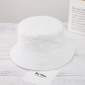 Detail of a minimalist white canvas sun hat on a wooden table with aesthetic cards