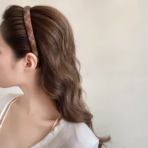 Close-up of a vintage brown plaid headband worn by a model with long wavy hair
