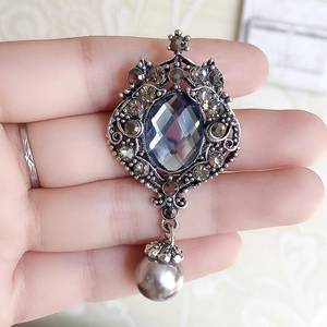 Detail of vintage baroque brooch with grey gemstones and elegant pearl drop pendant