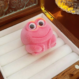 Macro shot of a cute pink frog-shaped velvet jewelry box on a vintage wooden background