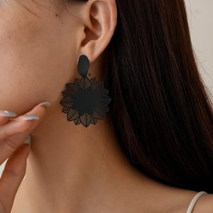 Close-up of a large black hollow geometric floral earring on a female model