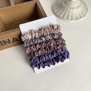 Detail of five-piece satin silk scrunchie set in earth tones on white display card