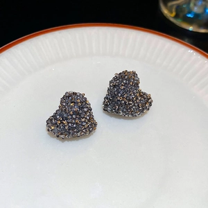 Vue macro de boucles d'oreilles cœur en métal gris avec cristaux pavés sur une assiette