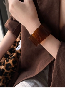 Macro shot of wide amber resin bracelet featuring marble texture on a brown blazer background