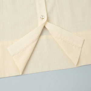 Close-up of a cream-colored shirt showing the linen texture and pearlescent button detail