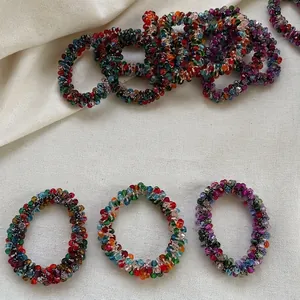 Handmade colorful crystal beaded hair ties on a minimalist beige linen background