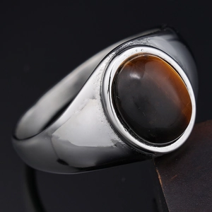 Macro d'une pierre œil-de-chat marron ovale sur une bague en acier poli brillant