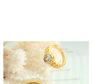 Close-up of golden ring featuring vertical striped texture and a round clear gemstone