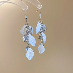 Detail of elegant silver tassel earrings featuring white shell teardrop pendants on stand