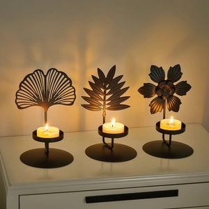 Nordic black metal leaf candle holders casting artistic plant shadows on a wall