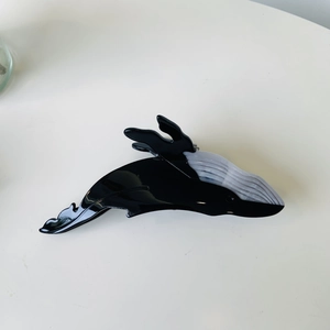 Detail of whale-shaped acetate hair claw clip with black and grey marble texture finish