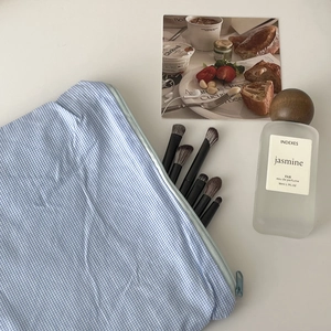Detailed top view of a blue plaid makeup bag with brushes on a clean white background