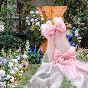 Large pink mesh bow decoration for weddings and outdoor parties in a garden setting