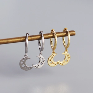 Detail of moon-shaped s925 silver hoop earrings with hollow star patterns in gold and silver