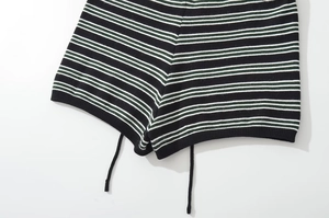 Detail of striped knit shorts with adjustable drawstring and fine texture in green and black