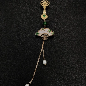 Détail de la broche en forme d'éventail avec jade, perles et glands en soie dorée