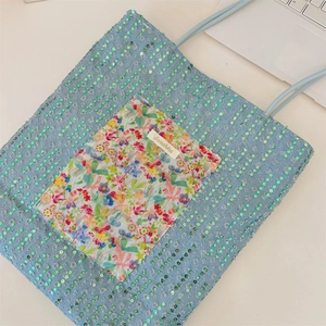 Detail of light blue canvas tote with green sequins and floral pocket applique