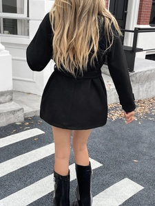 Back view of a stylish black short wool coat for women in an elegant urban street setting