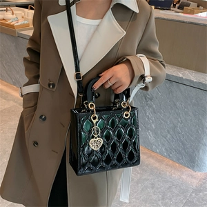 Glossy patent leather tote bag with quilted pattern and gold heart charm in dark green
