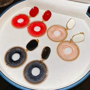 Dettaglio di orecchini geometrici colorati con texture intrecciata e bordi in metallo