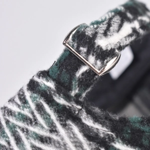 Macro detail of plaid wool baseball cap showing thick fabric texture and silver metal buckle