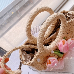 Detail of straw handbag featuring pink tulip flowers, pearl accents, and polka dot lining