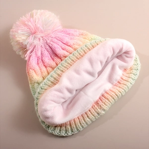 Detailansicht der Regenbogen-Strickmütze mit dickem Fleecefutter und flauschigem Bommel