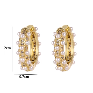 Detailed view of gold earrings with pearls and cubic zirconia, size 2cm by 0.7cm