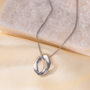 Detail of silver twisted oval pendant necklace on white stone and beige silk background